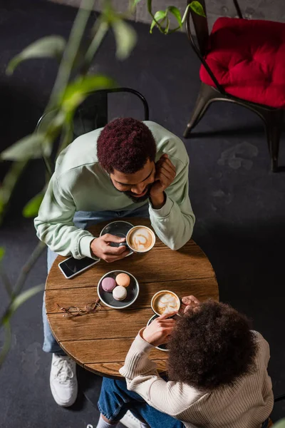 Overhead view of young african american coupe holding coffee cups during date in cafe — Stock Photo