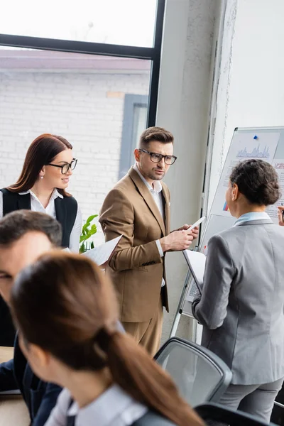 Interrassische Geschäftsleute arbeiten in der Nähe von Flipchart im Büro — Stockfoto