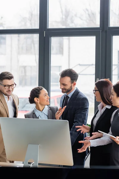 Afroamerikanische Geschäftsfrau zeigt auf Kollegin in der Nähe von Computer im Büro — Stockfoto