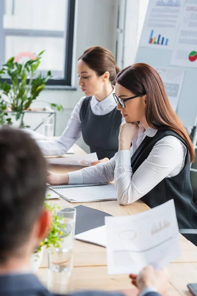 Imprenditrici che lavorano con documenti vicino a un uomo d'affari offuscato — Foto stock