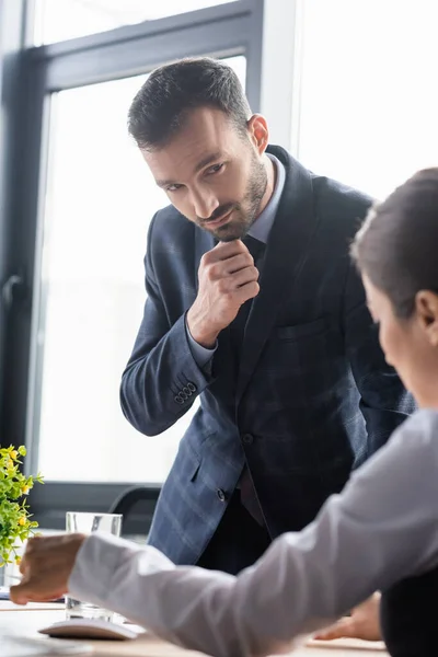 Businessman in formal wear looking at blurred colleague in office — Stock Photo