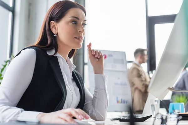 Geschäftsfrau in offizieller Kleidung im Büro mit Computer im verschwommenen Vordergrund — Stockfoto