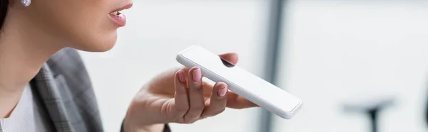 Vista recortada de la mujer de negocios grabación de mensajes de audio en el teléfono inteligente, bandera - foto de stock