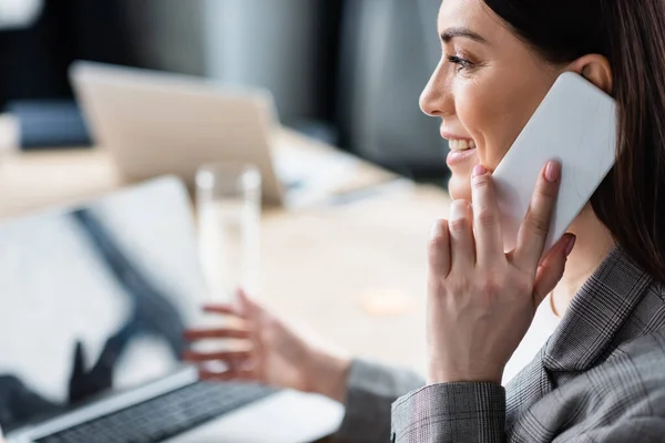 Vue latérale du gestionnaire souriant parlant sur smartphone au bureau — Photo de stock