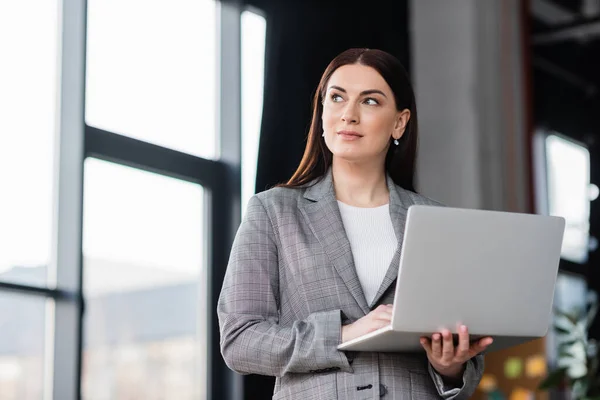 Donna d'affari in abbigliamento formale che tiene il computer portatile in ufficio — Foto stock