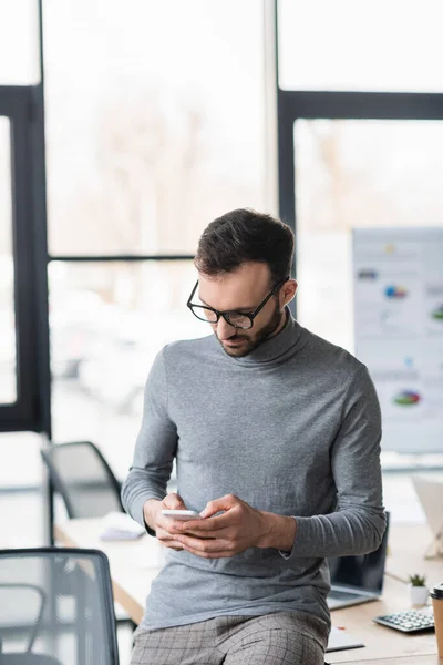 Uomo d'affari in occhiali da vista utilizzando il telefono cellulare in ufficio — Foto stock