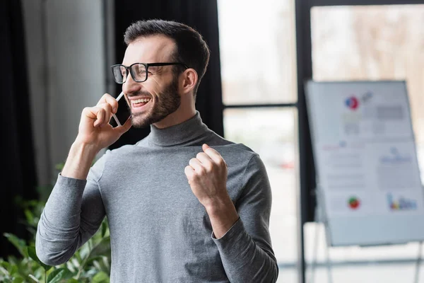 Excited businessman showing yes gesture while talking on smartphone — Stock Photo