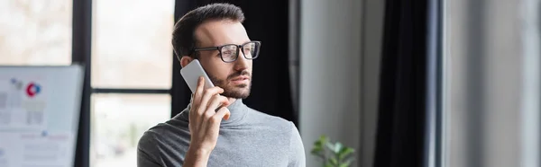 Bearded businessman in eyeglasses talking on smartphone, banner — Stock Photo