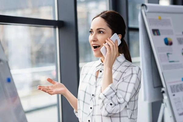 Aufgeregte Geschäftsfrau spricht im Büro auf Smartphone — Stockfoto