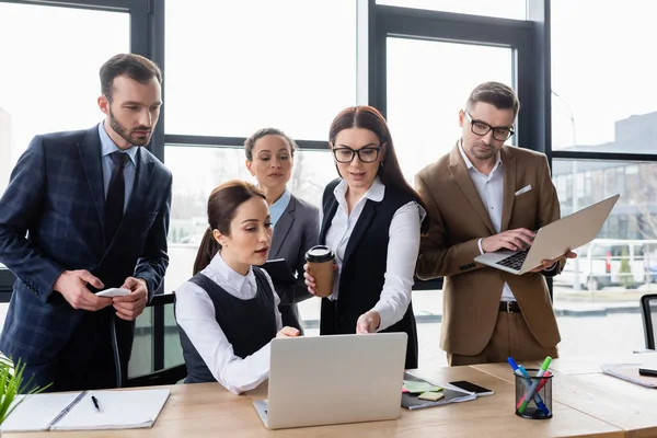 Les gens d'affaires interraciaux utilisant un ordinateur portable tout en travaillant ensemble au bureau — Photo de stock