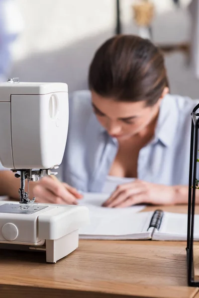 Nähmaschine nahe Näherin auf verschwommenem Hintergrund im Atelier — Stockfoto