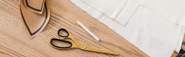 High angle view of cloth, scissors and sewing pattern on table, banner — Stock Photo