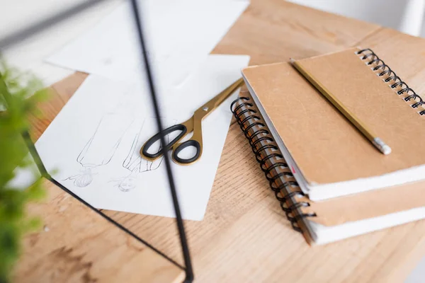 Sketches near scissors and notebooks on table — Stock Photo