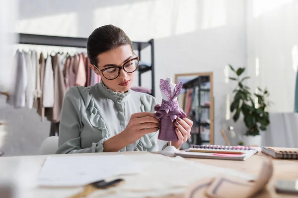 Designer in possesso di manichino con abito vicino notebook e stoffa sfocata — Foto stock