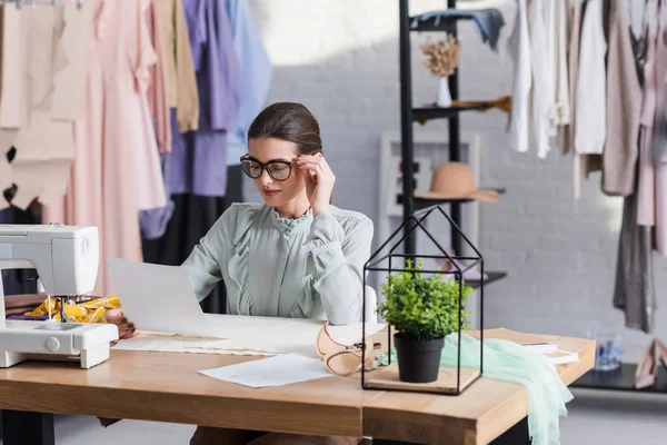 Couture regardant croquis près de tissu et machine à coudre — Photo de stock