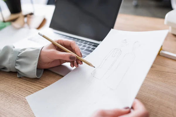 Cropped view of designer drawing sketch near blurred laptop on table — Stock Photo