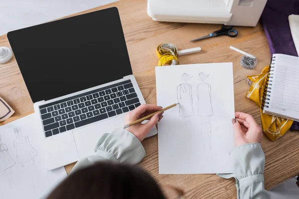 Vue aérienne des croquis de dessin de concepteur près de l'ordinateur portable et de la machine à coudre — Photo de stock