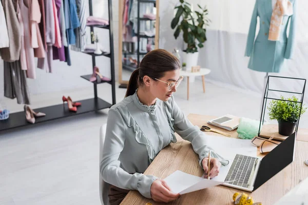 Designer zeichnen Skizze in Laptopnähe mit leerem Bildschirm und Maßband im Atelier — Stockfoto