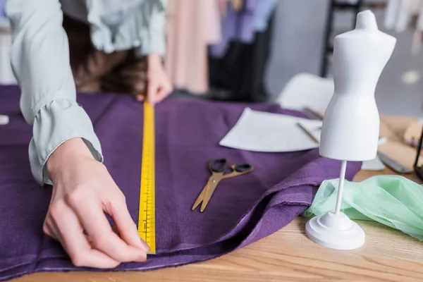 Cropped view of designer measuring cloth near mannequin and scissors — Stock Photo