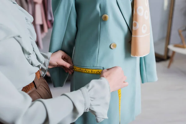 Cropped view of seamstress measuring pocket of blazer in atelier — Stock Photo