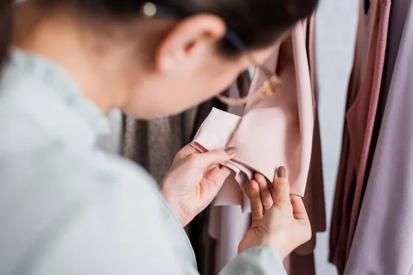 Costureira borrada olhando para mangas de roupas no atelier — Fotografia de Stock
