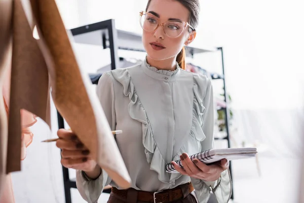 Young seamstress with notebook holding sewing pattern — Stock Photo