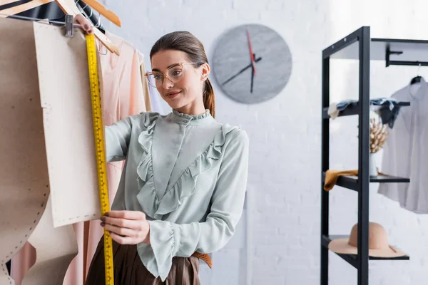 Designer sorridente che misura il modello di cucito in atelier — Foto stock