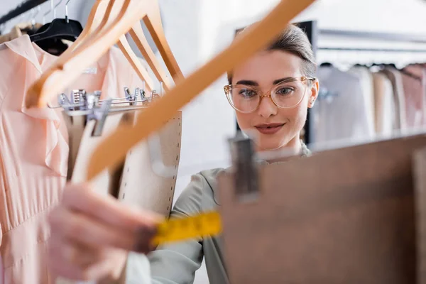 Alegre diseñador que mide el patrón de costura en primer plano borroso — Stock Photo