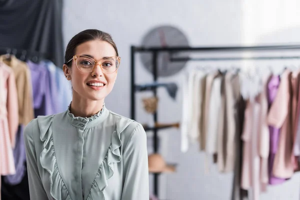 Designer alegre em óculos olhando para a câmera no atelier — Fotografia de Stock