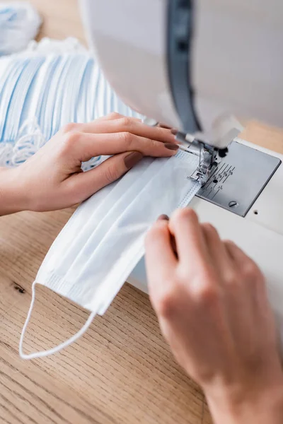 Ausgeschnittene Ansicht einer Näherin, die medizinische Maske auf verschwommener Maschine näht — Stockfoto