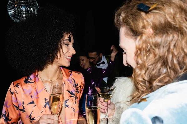 Happy multiracial friends having drink in night club on black background — Stock Photo