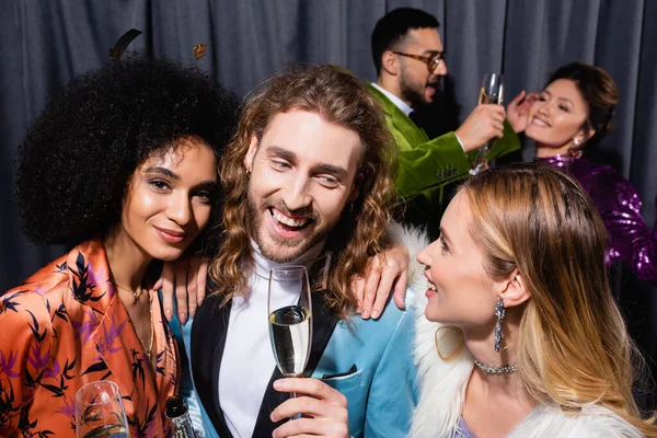 Усміхнені міжрасові друзі в стильному одязі, що п'є шампанське на сірому фоні — стокове фото