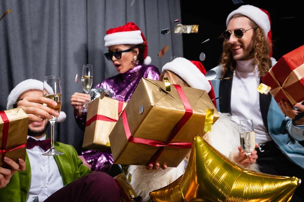 Glückliche interrassische Freunde feiern Neujahr in der Nähe von grauen Vorhang auf schwarzem Hintergrund — Stockfoto