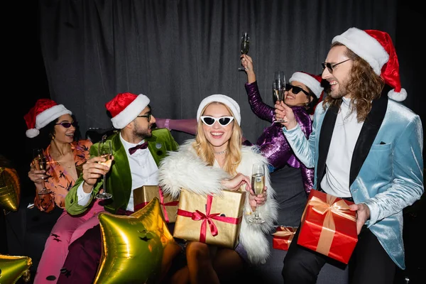 Lächelnde gemischtrassige Freunde feiern Neujahr auf grauem Hintergrund — Stockfoto