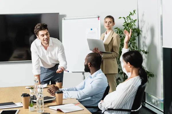 Empresário animado apontando com caneta perto de equipe de negócios interracial na sala de conferências — Fotografia de Stock