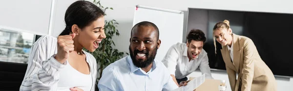 Animado Africano americano empresária mostrando triunfo gesto perto sorrindo colegas, banner — Fotografia de Stock