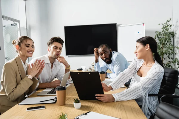 Aufgeregte multiethnische Geschäftspartner blicken auf Klemmbrett in den Händen lächelnder afrikanisch-amerikanischer Geschäftsfrau — Stockfoto