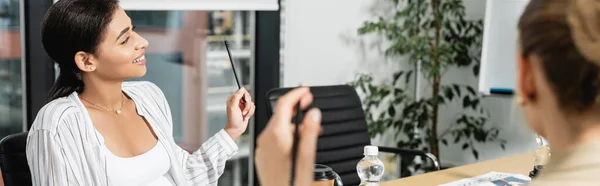 African american businesswoman smiling near blurred colleague in conference room, banner — Stock Photo