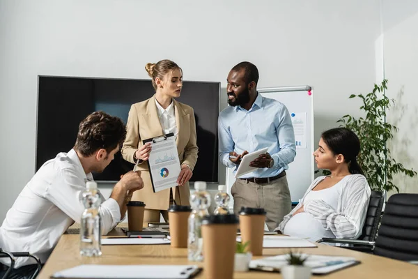 Afrikanischer amerikanischer Geschäftsmann zeigt bei Diskussion mit multiethnischen Kollegen auf digitales Tablet — Stock Photo