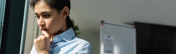 Pensive african american businesswoman holding hand near face while thinking in office, banner — Stock Photo