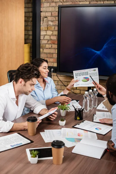 Businesswoman pointing at document with analytics near multicultural business people — Stock Photo