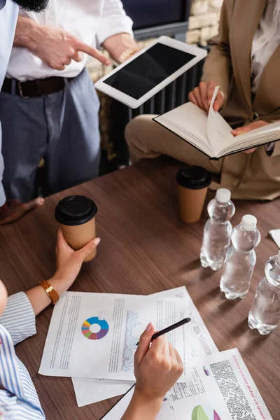 Partial view of businessman pointing at digital tablet near multiethnic colleagues in conference room — Stock Photo