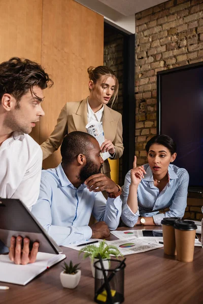 African american businesswoman showing idea gesture near interracial colleagues — Stock Photo