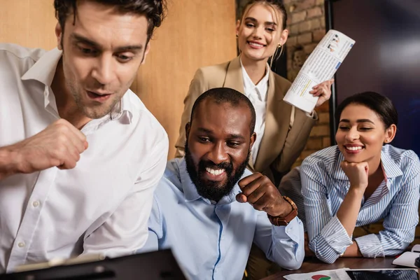 Colegas de negocios multiétnicos emocionados mostrando gesto de victoria en primer plano borroso - foto de stock