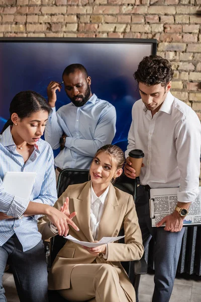 African american businesswoman pointing at document near multicultural coworkers — Stock Photo