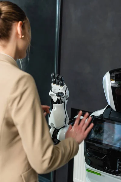 Junge Geschäftsfrau berührt Roboter im Büro — Stockfoto