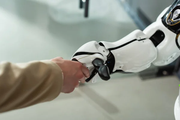 Partial view of businesswoman shaking hands with robot in office — Stock Photo