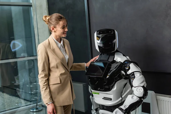 Joyful businesswoman standing near robot in office — Stock Photo