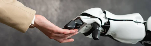 Cropped view of businesswoman touching hand of robot, banner — Stock Photo