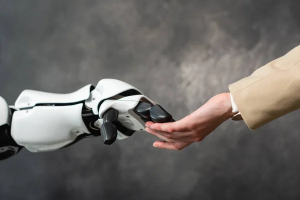 Cropped view of businesswoman touching hand of humanoid robot — Stock Photo